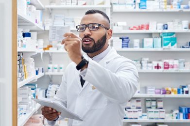 young pharmacist working on a digital tablet inside of a pharmacy during the day